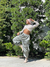 a woman is posing in front of bushes